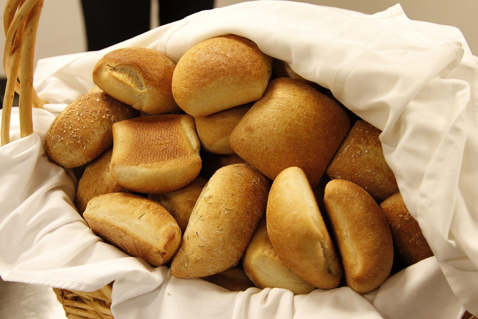 Brotkorb mit hellen Brötchen und Laugengebäck, ausgelegt mit einem weißen Stofftuch
