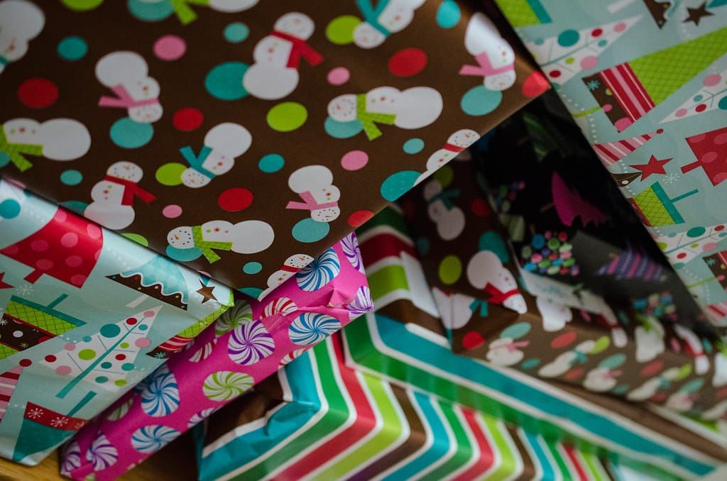 Mehrere Weihnachtsgeschenke in buntem Geschenkpapier mit Schneemännern, Tannenbäumen und Streifen