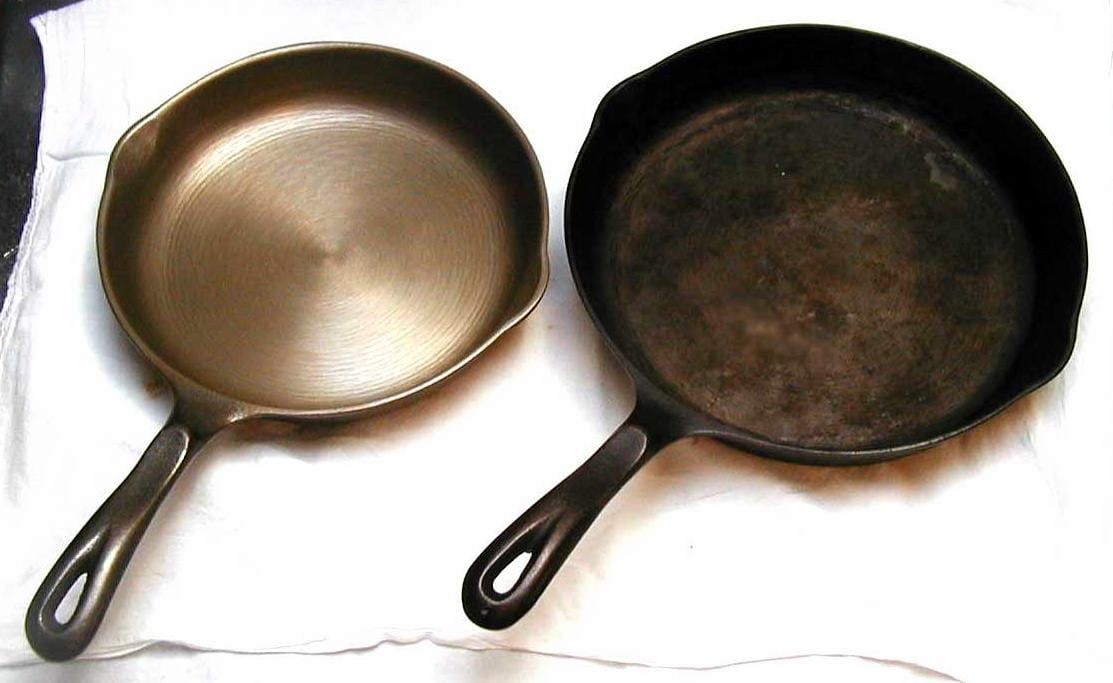 Zwei gusseiserne Bratpfannen nebeneinander auf einem weißen Tuch, eine blank, eine dunkel eingebrannt
