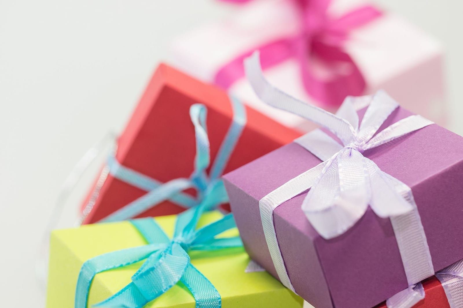 Bunte Geschenkschachteln mit Satinschleifen in Lila, Rot und Gelbgrün