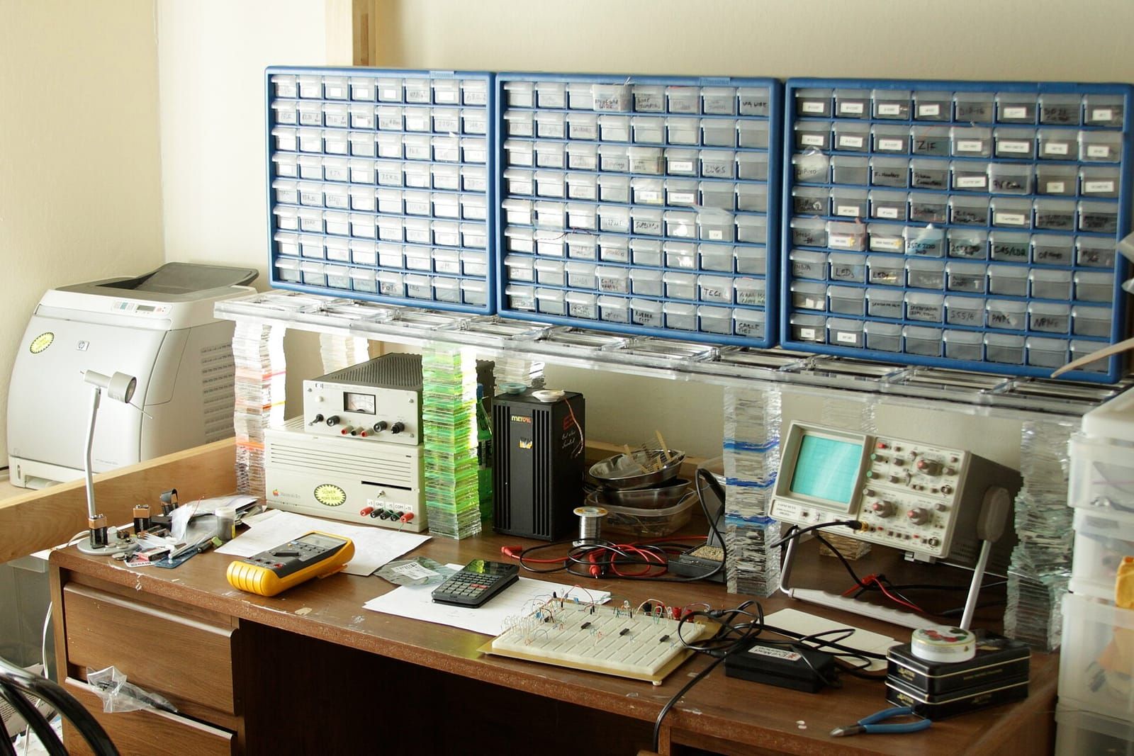 Elektronik-Arbeitsplatz mit Lötstation, Oszilloskop, Steckbrett und Sortierkästen voller Bauteile