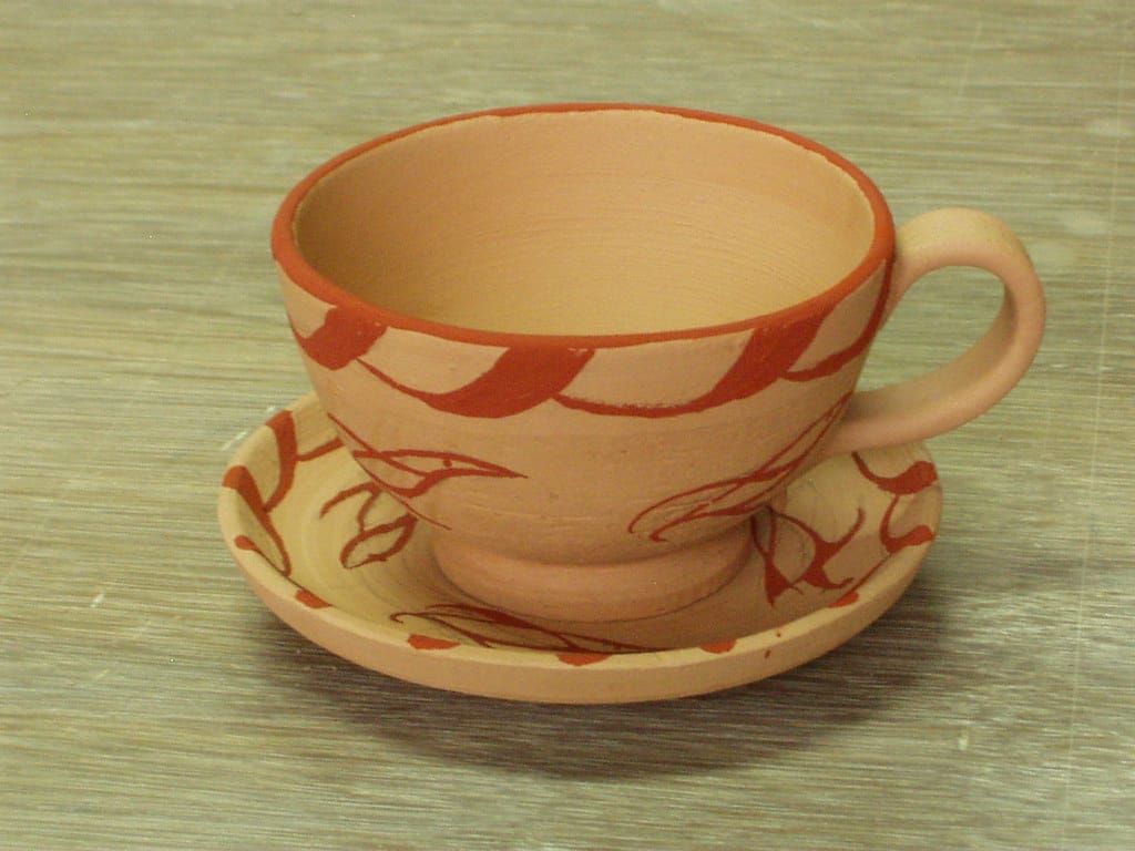 Hellbraune Keramiktasse mit Untertasse, rot bemalt mit Ranken und Blättern